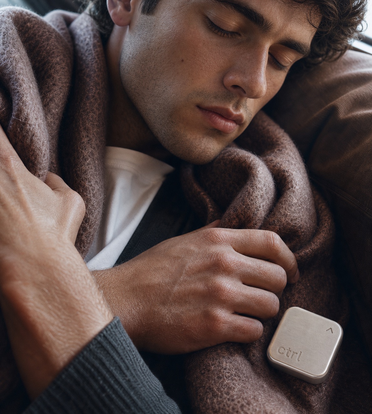 A man asleep under a wool blanket with the ctrl key resting on top